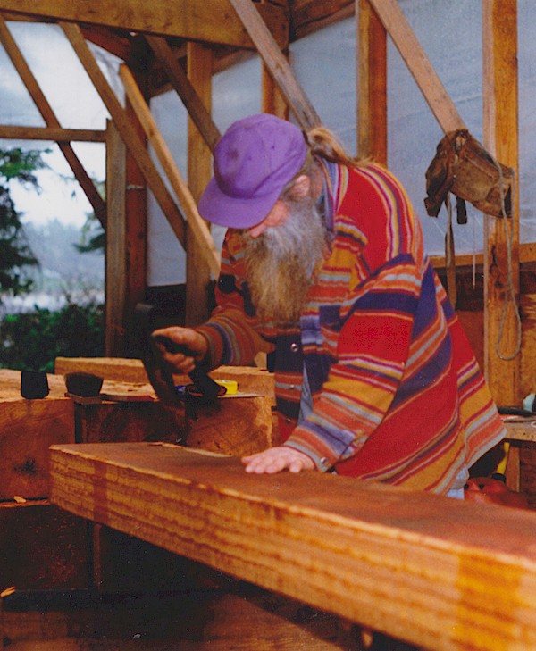 Henry Nolla carving cedar with his adze inside his carving shed