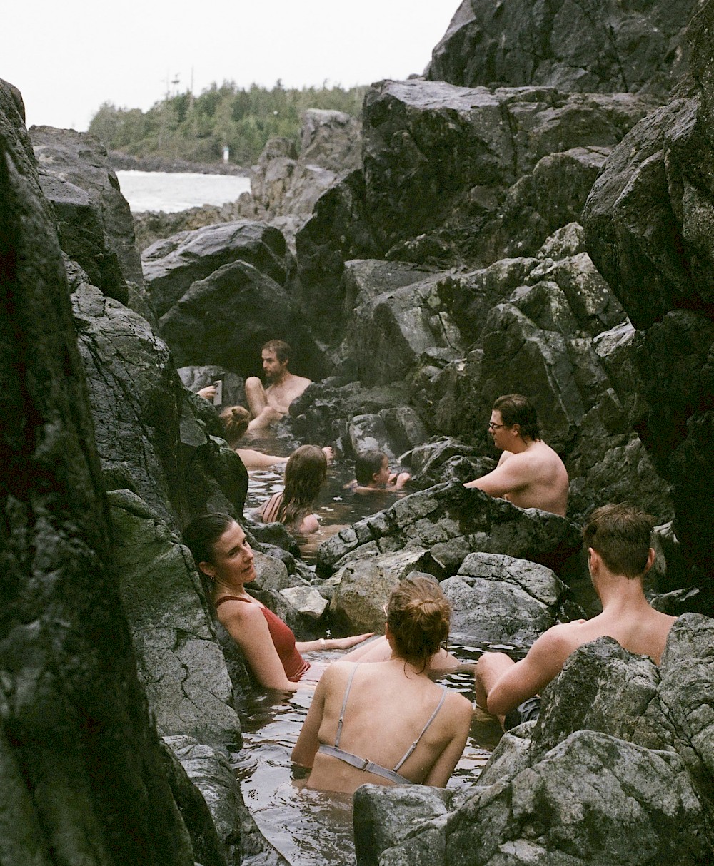 Individuals relaxing in a natural rocky hot springs, oceanside.