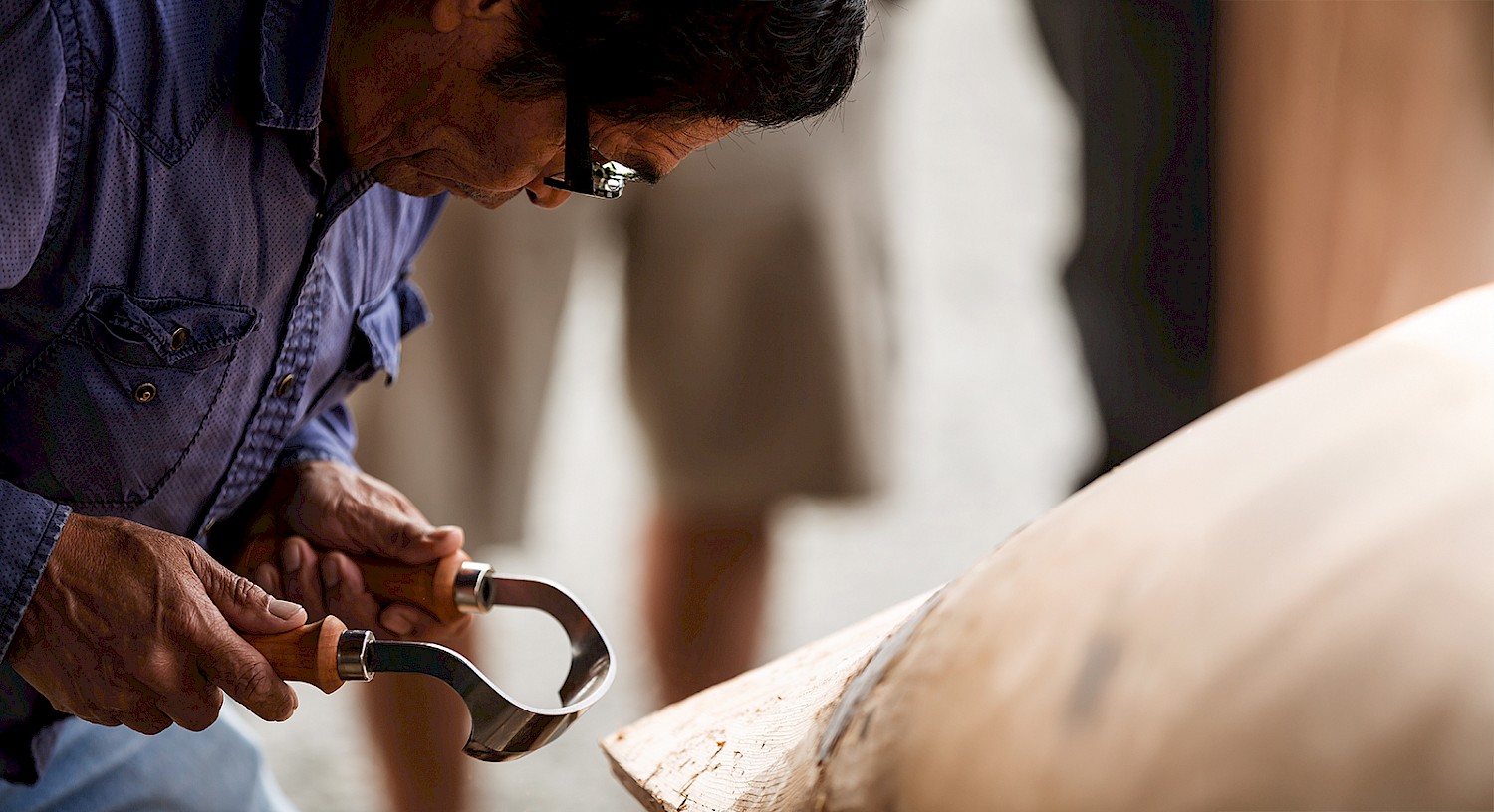 A first nations carver working on a dugout canoe, focused intently on their work in a workshop setting