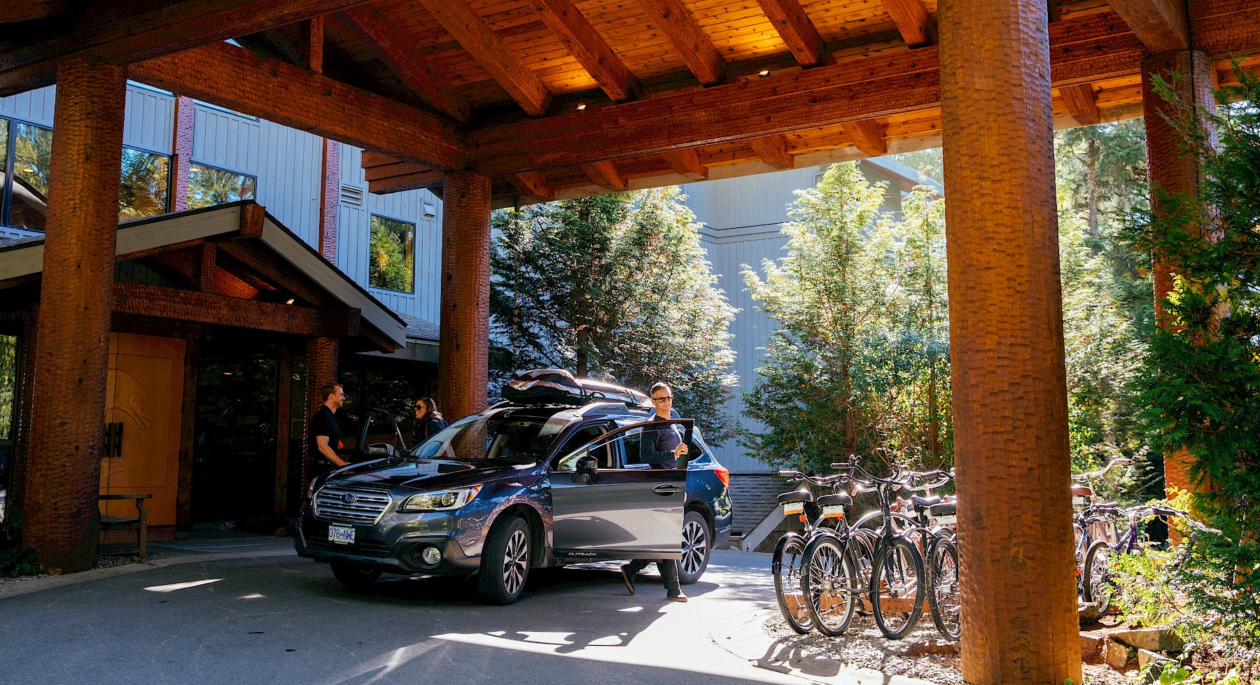Guests arriving beneath the covered entrance of the Wickaninnish Inn, with parked bicycles and adzed cedar beams