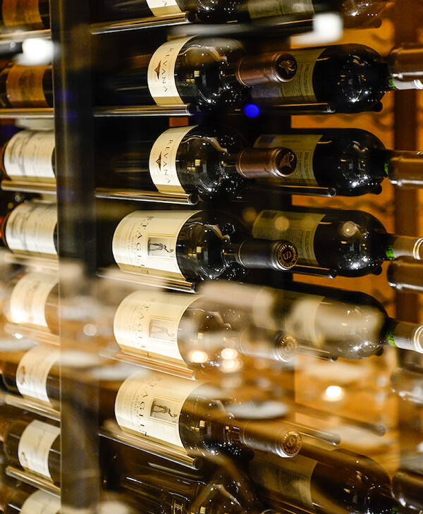 A close-up view of a wine rack filled with bottles of various wines. The bottles are stored horizontally, with labels visible.