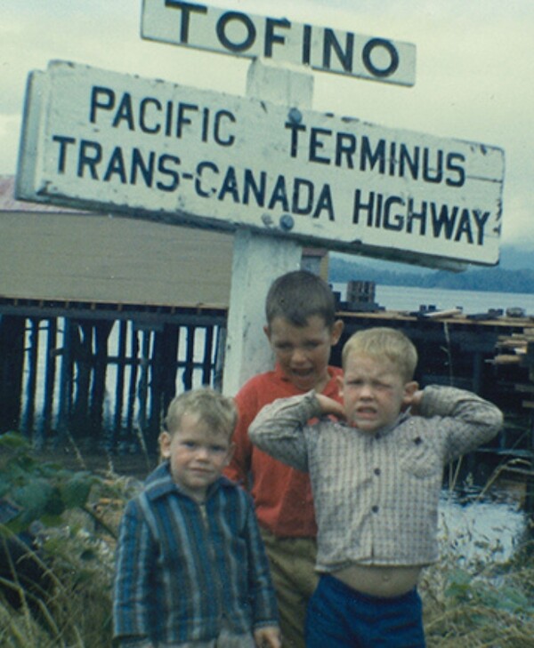 Charles and his brothers as children in front of a sign that reads
