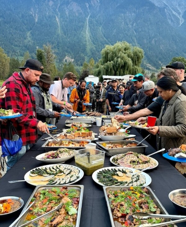 Table of delicious food surrounded by attendees of CooksCamp