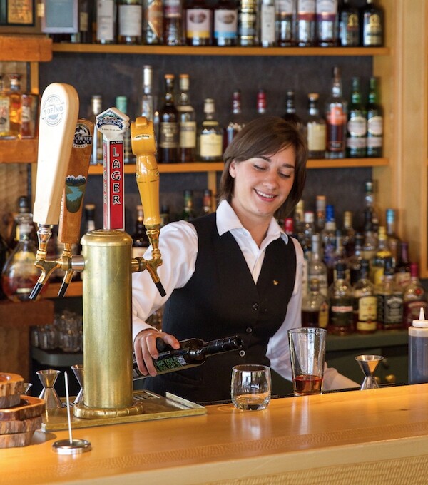 Server smiles as she pours a glass behind the original On the Rocks Bar